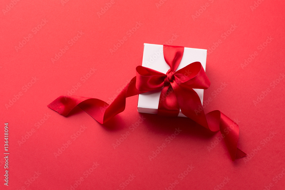 White Gift box with red ribbon on red background. Holiday Birthday Valentines day concept. Top view White Gift box with red ribbon on red background. Holiday Birthday Valentines day concept. Top view