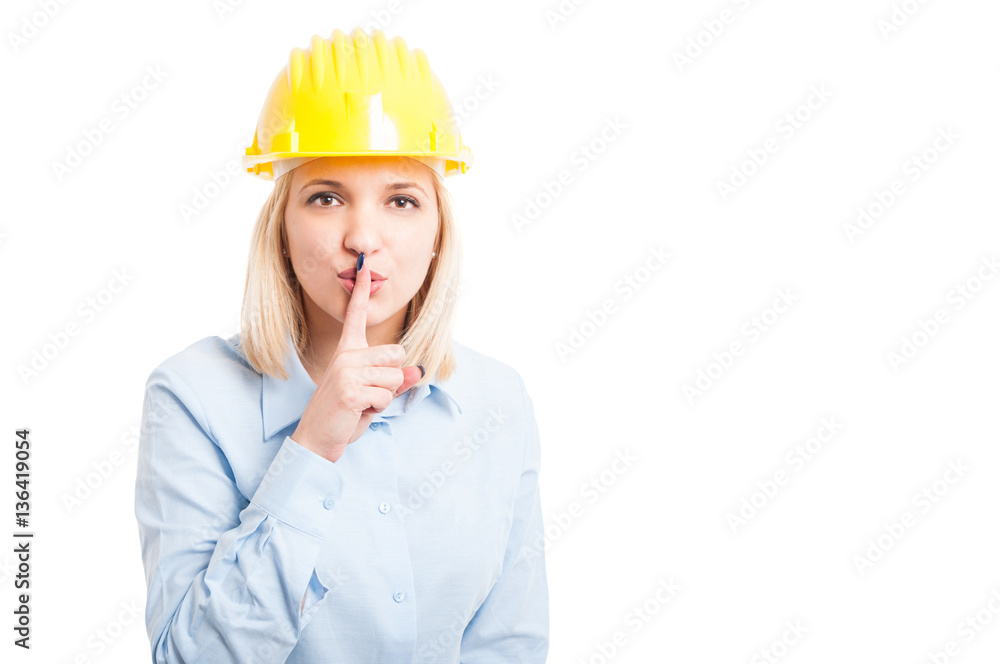 Female architect wearing helmet making sush or silence gesture Female architect wearing helmet making sush or silence gesture