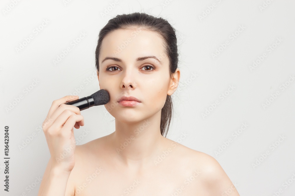 woman holds brush for make-up on face woman holds brush for make-up on face