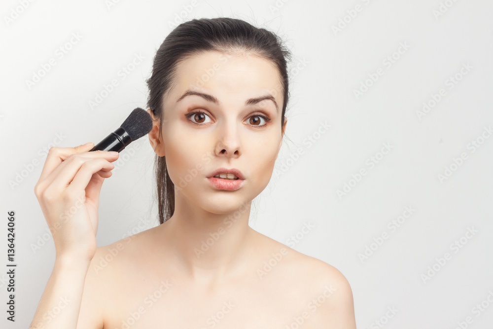 pretty woman with makeup brush looking at camera pretty woman with makeup brush looking at camera