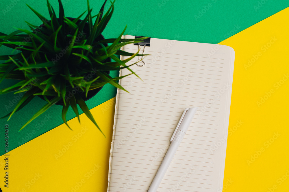 a notebook with a clip, a pen and a flower in a pot a notebook with a clip, a pen and a flower in a pot