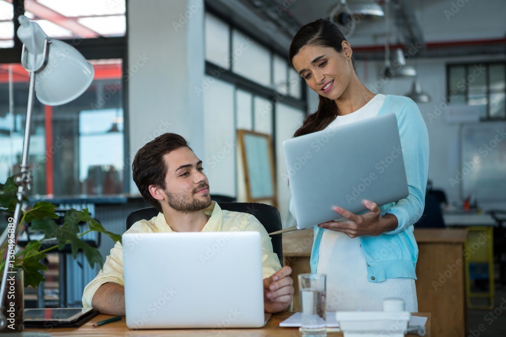 Business executives discussing over laptop Business executives discussing over laptop