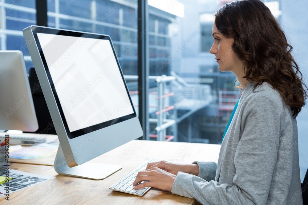 Female graphic designer working over computer at desk Female graphic designer working over computer at desk