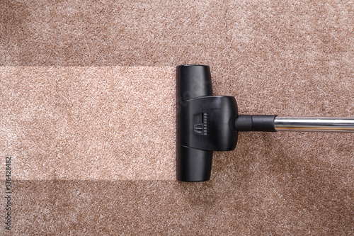 Vacuuming carpet with vacuum cleaner. Housework service. Close up of the head of a sweeper cleaning device.