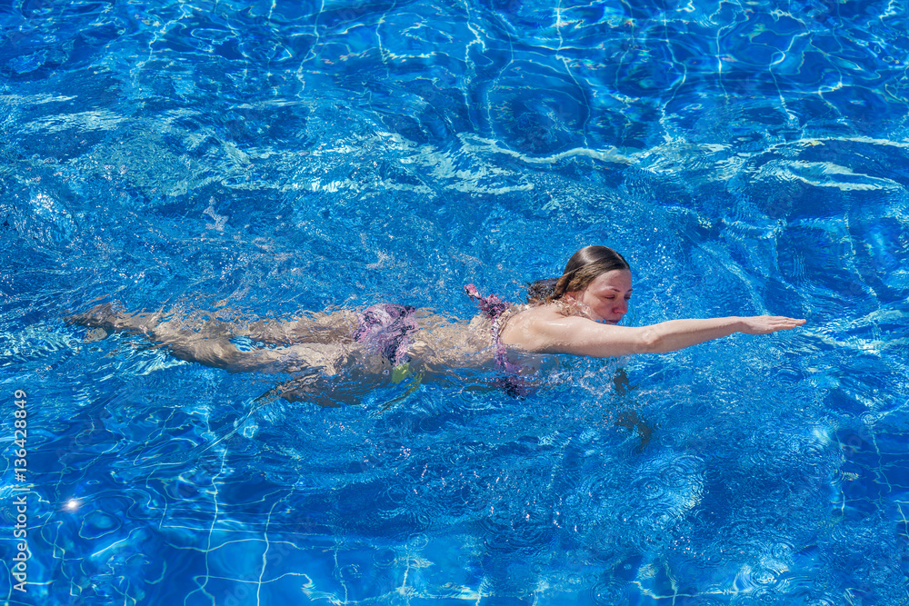 Woman in bikini swims in the pool
