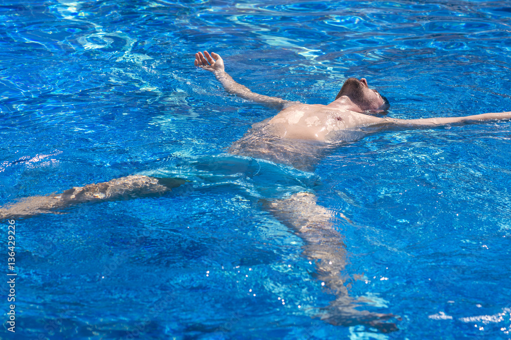 Man in blue shorts lying on the water