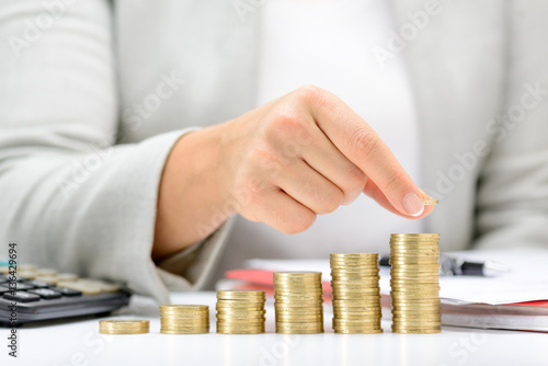 Female hand putting money coin stack growing business, saving money concept. photo