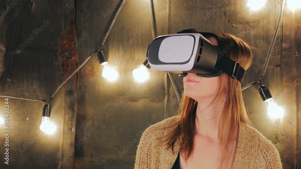 Young woman using Virtual Reality Glasses. Virtual reality mask. VR. Retro loft Christmas background with light bulbs