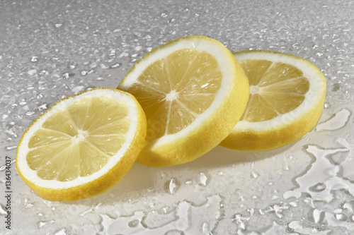 Zitrone aufgeschnitten auf weissen Hintergrund mit Wassertropfen