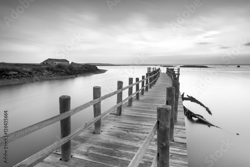 Ancient pier and abandoned boat at black and white fine art photography 