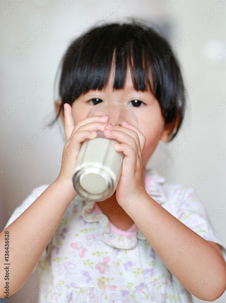 Close up of little girl in pajamas drinking milk from glass indoor at the morning. Close up of little girl in pajamas drinking milk from glass indoor at the morning.