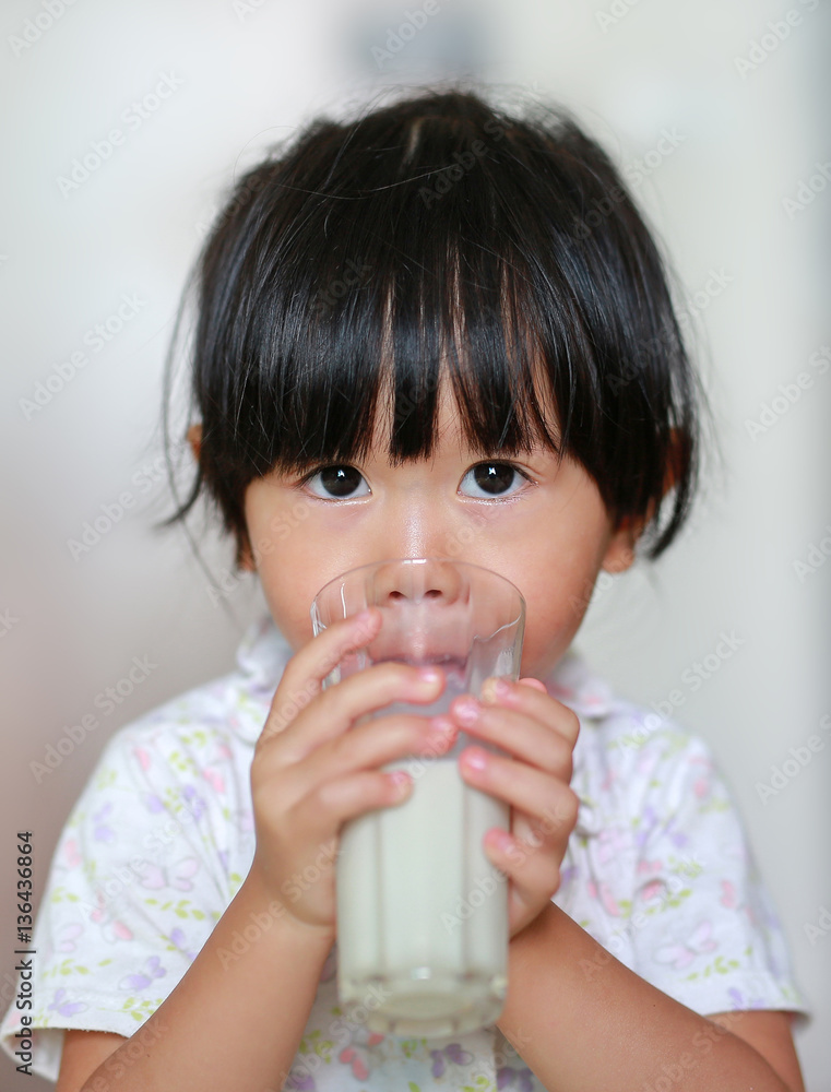 Close up of little girl in pajamas drinking milk from glass indoor at the morning. Close up of little girl in pajamas drinking milk from glass indoor at the morning.