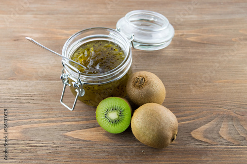 Kiwi jam in a glass jar on a wooden background