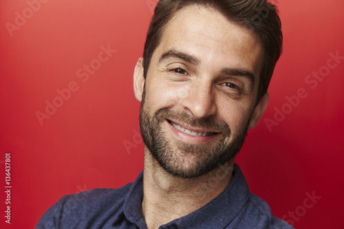 Smiling guy against red background, portrait