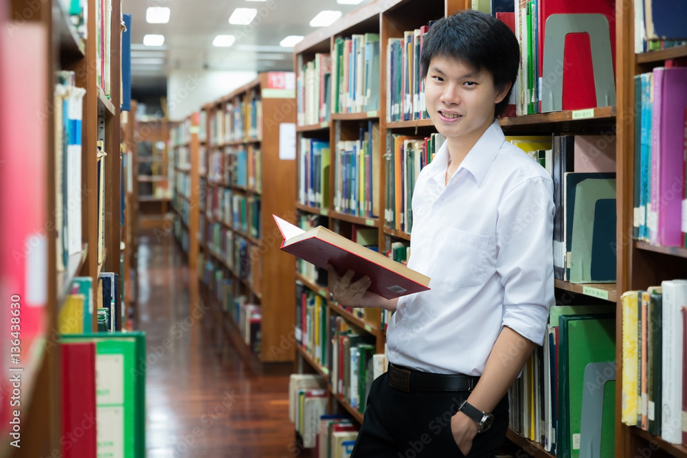 Asian student in uniform reading in the library at university Asian student in uniform reading in the library at university