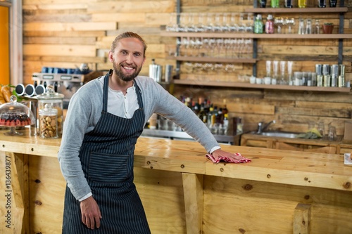 Waiter wiping counter with napkin in café