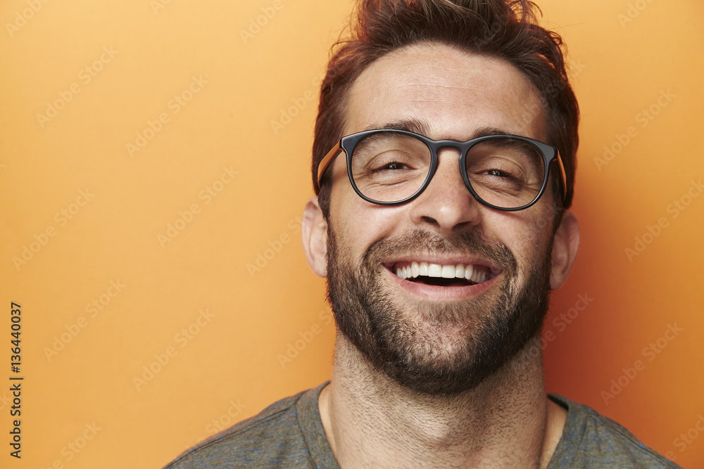 Man laughing in orange studio, close up - obrazy, fototapety, plakaty 