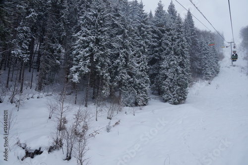 
Chairlift with skiers rises up in the mountains in winter photo