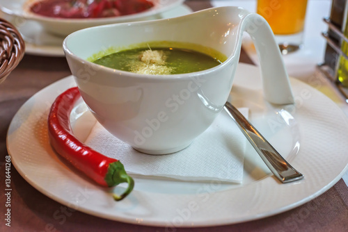 Spinach cream soup with chili in a white bowl