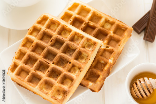 Traditional breakfast: coffee, belgian waffles with honey and chocolate sauce on white wooden table. Selective focus