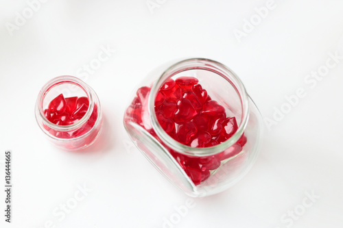 Big and little love: two glass jars of different sizes with red glass heartlets on white background