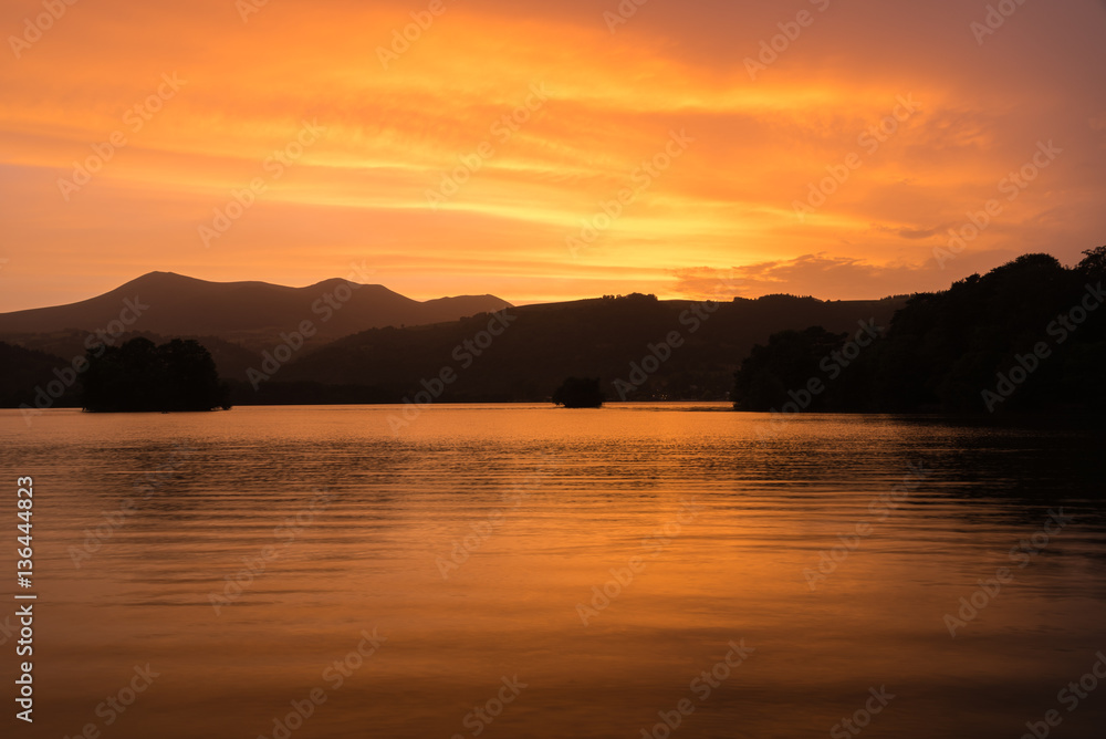 Coucher de soleil en Auvergne autour du Lac Chambon. Nuages oranges et jaunes. Coucher de soleil en Auvergne autour du Lac Chambon. Nuages oranges et jaunes.