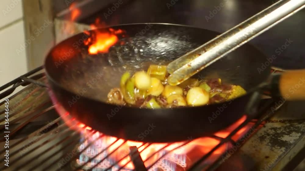 Asian restaurant, chinese chef cooking food with red meat beef and vegetables in wok pan on fire. Stir fry pan with flames. Slow motion. Asian restaurant, chinese chef cooking food with red meat beef and vegetables in wok pan on fire. Stir fry pan with flames. Slow motion.