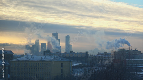 Air pollution from industrial plants. Large plant on the background of the Moscow City. Pipes throwing smoke in the sky. Cold russian winter. Smoke from an industrial thermal chimney, power plant.