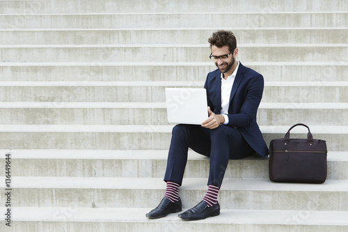 Businessman on laptop with briefcase on steps