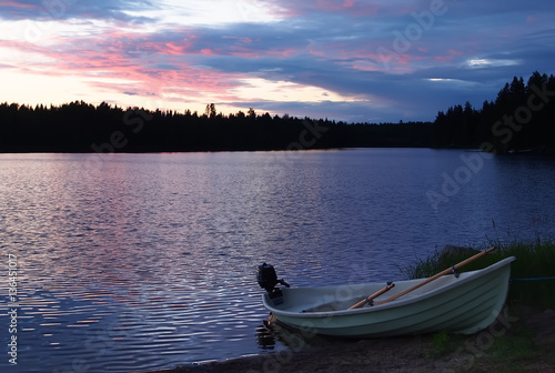 Sunset on the lake with fishing boat on the shore in Finland