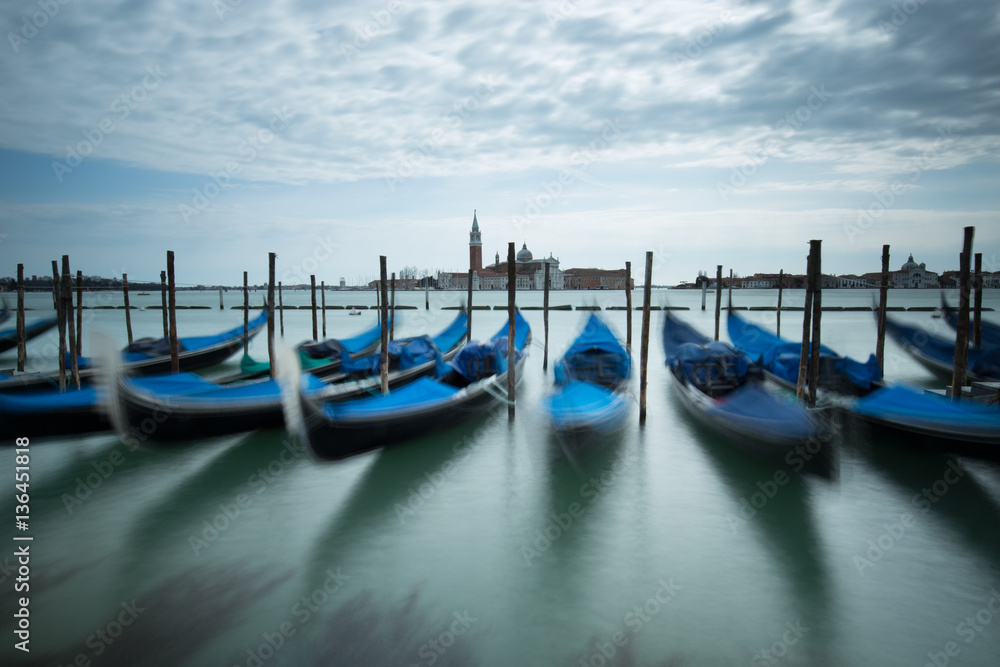 View of Gondolas tied up at the side of the grand canal waiting on tourists.  Showing view over the Grand Canal in Venice.