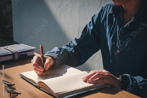 male hand writing in notebook with pen in Home