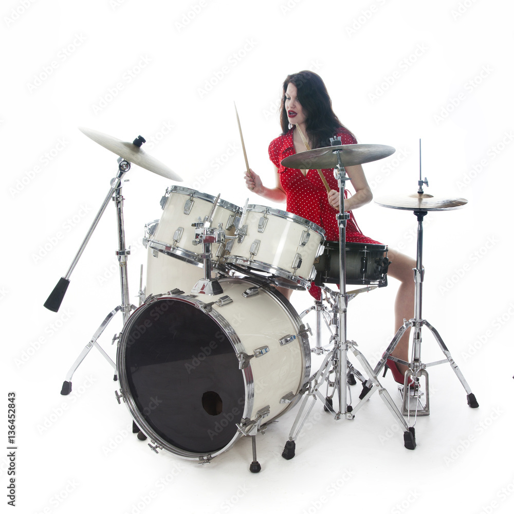 Fototapeta premium sexy brunette in red dress plays drum kit in studio