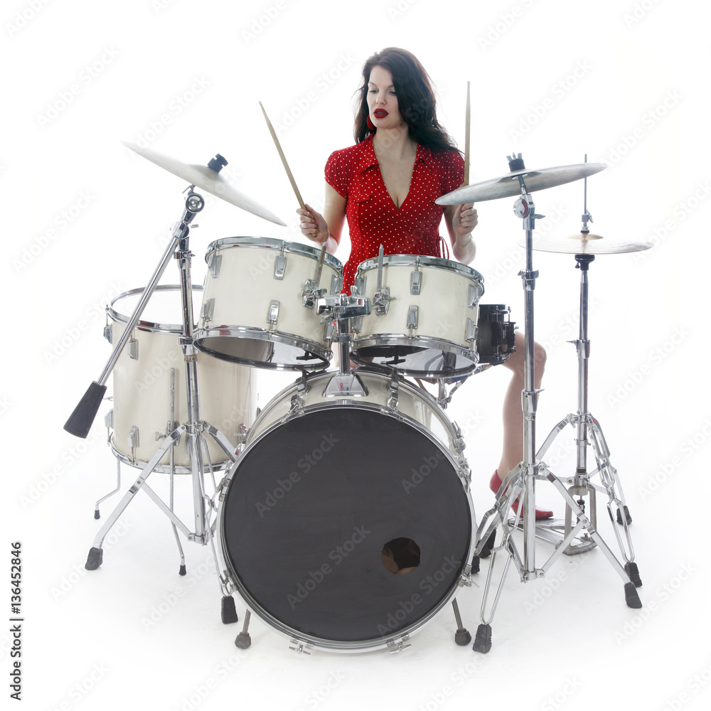 Fototapeta premium sexy brunette in red dress plays drum kit in studio