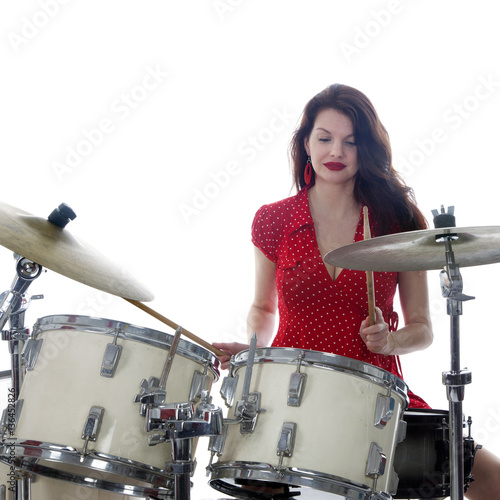 sexy brunette in red dress plays drum kit in studio photo