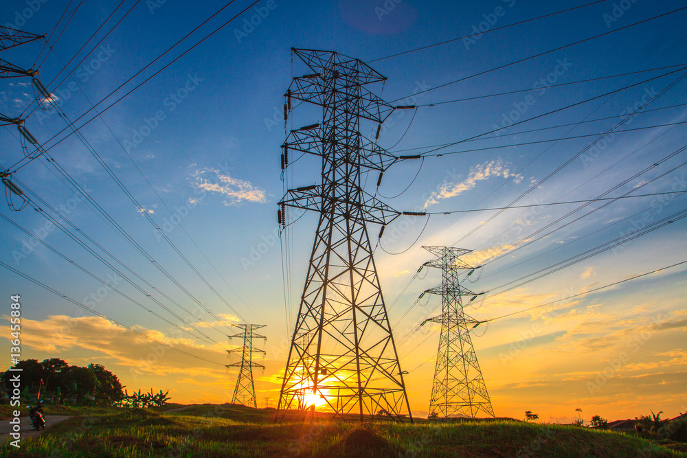 Fototapeta premium Wysokie napięcie w wieży transmisyjnej o porannym wschodzie słońca z pięknem błękitnego nieba