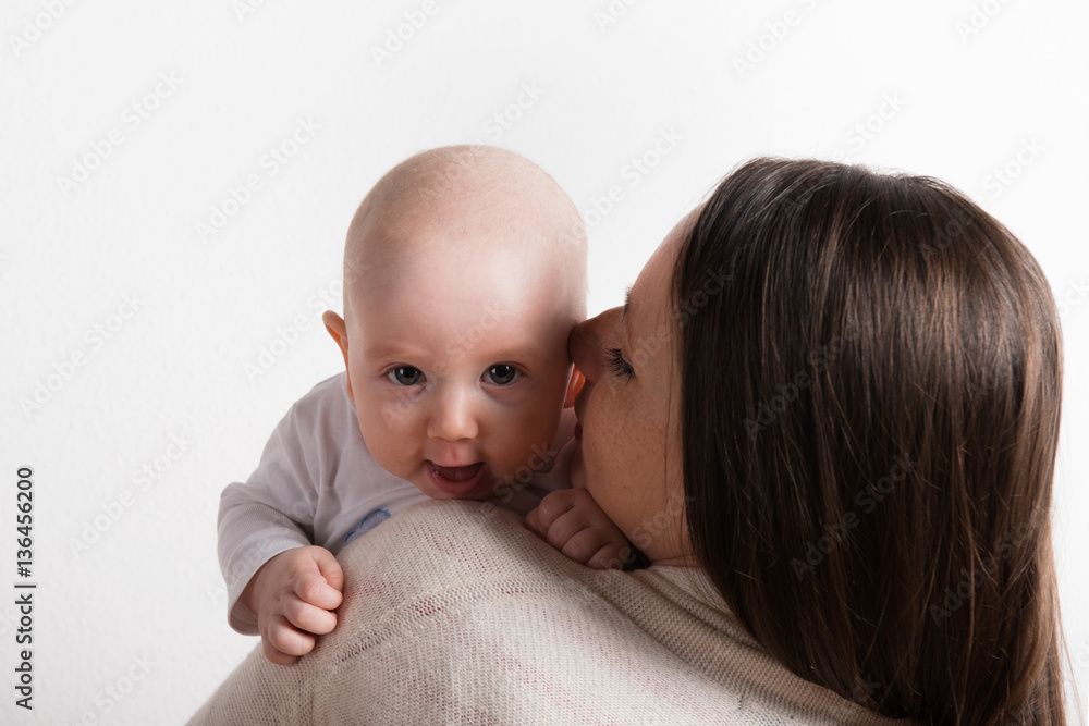 Beautiful mother holding baby son in her arms. Studio shot. Beautiful mother holding baby son in her arms. Studio shot.