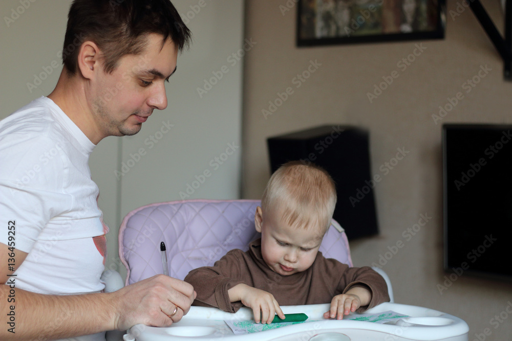 Family at home: young father and his cute little son drawing tog Family at home: young father and his cute little son drawing tog