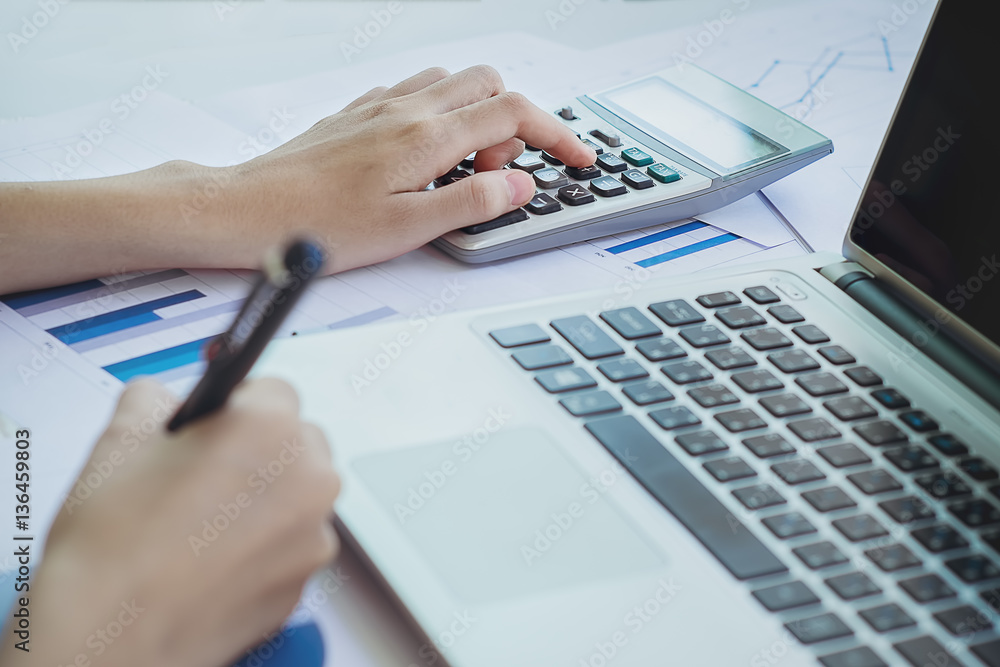 Asian Business woman using a calculator to calculate the numbers Asian Business woman using a calculator to calculate the numbers