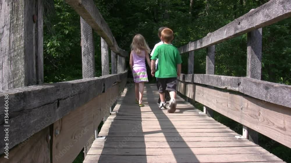 Group of 3 kids walking across bridge.
Group of 3 kids walking across bridge.
