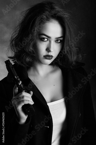 serious girl with gun on black background, monochrome