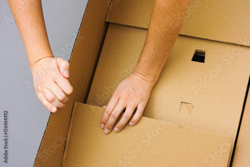 Two woman hands opening big cardboard box