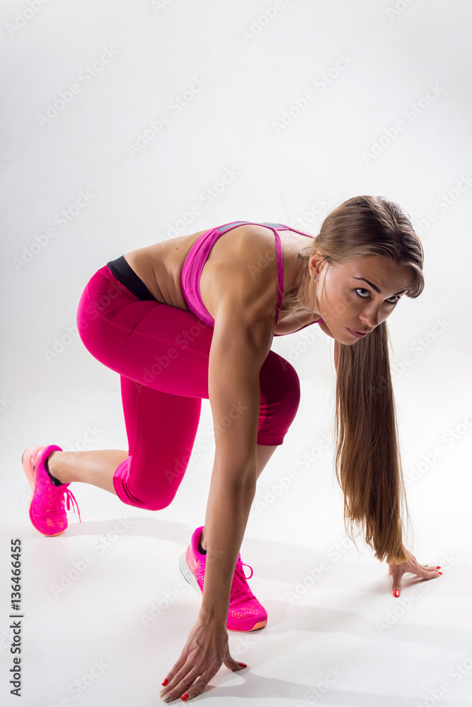 A woman dressed in sportswear prepared to run. Studio. White bac A woman dressed in sportswear prepared to run. Studio. White bac