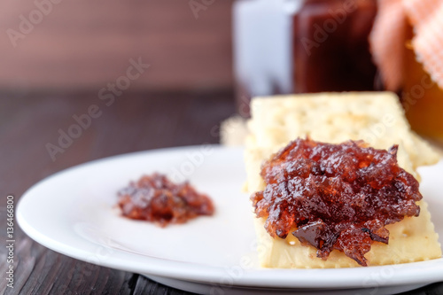 Crackers with grape jam on wooden background