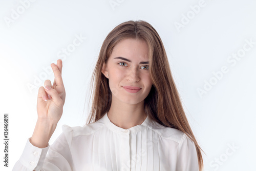 young girl in the white blouse holding hand with crossed fingers is isolated on background