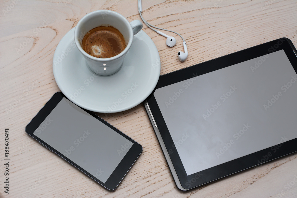 Top view of tablet, cell phone, earphones and coffee on wooden table. Top view of tablet, cell phone, earphones and coffee on wooden table.