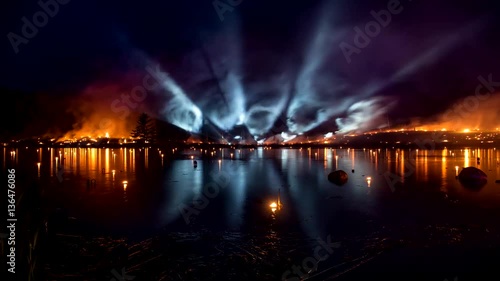 Burning grass with bright light tubes over the lake photo