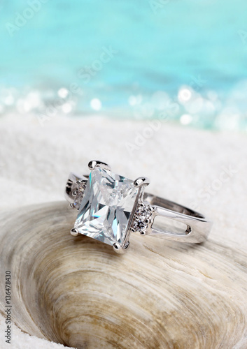 Jewelry ring with clean diamond on sand beach background, soft f