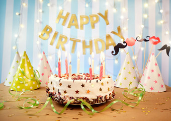 Happy birthday cake with candles on the background of garlands and letters.