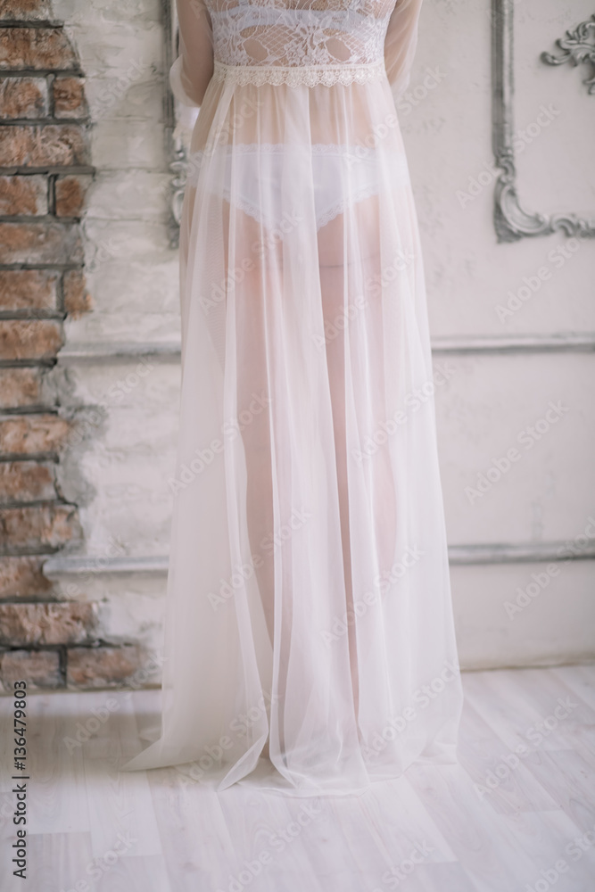 Girl in a white lace boudoir dress, from the waist booty legs near wall Girl in a white lace boudoir dress, from the waist booty legs near wall